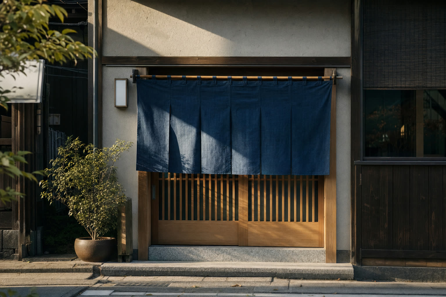 朝の光が差すお店の入口にかかる、藍色ののれん